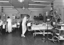 826708 Afbeelding van twee verpleegkundigen aan het bed van patiënten op de afdeling intensive care van het ...